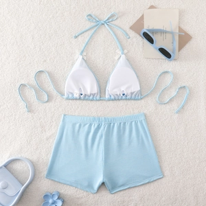 Detailed flat lay of blue gingham bikini set with white bow accents on fluffy background