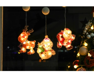 Detail of Santa, snowman, and reindeer LED suction cup lights glowing on a window pane