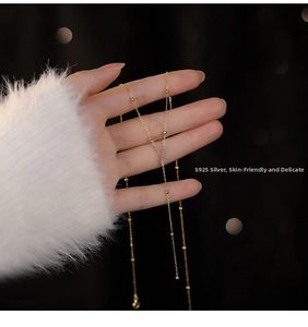 Detail of S925 sterling silver Y-shaped tassel necklace with gold-plated beads on fabric