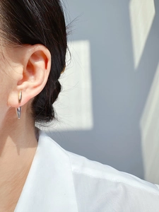 Detail of two-tone gold and silver rivet stud earring worn for a modern minimalist look