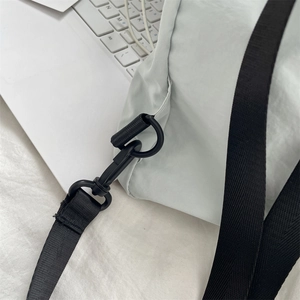 Detail eines hochfesten schwarzen Hakens und verstellbaren Gurts an hellgrauem Rucksack