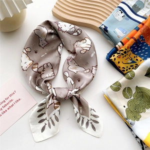 Silk-like square scarf featuring cat, leopard, and floral prints on elegant wooden stand