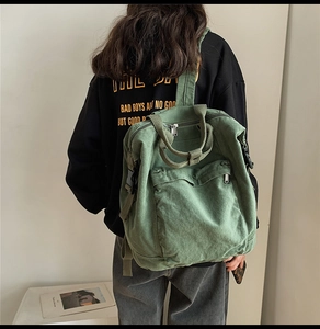 Detail of army green canvas backpack with side buckles and large front zip pocket