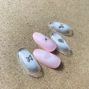 Detail of pink and white gradient nail stickers with butterfly, heart and rhinestone accents