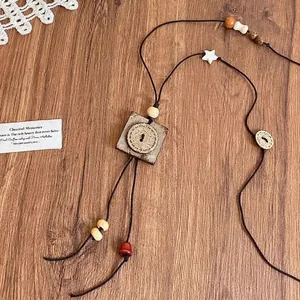 Close-up of vintage ethnic necklace with square wood pendant and star beads