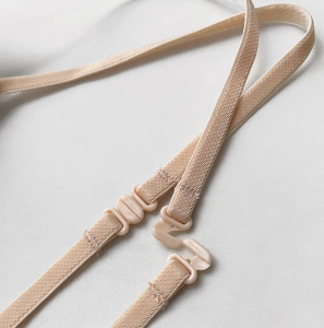 Detail view of skin-colored adjustable bra straps with plastic buckles and hooks