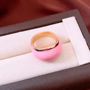 Anello tondo minimalista in smalto rosa con finitura dorata in una scatola di lusso