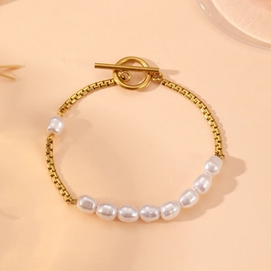 Goldenes OT-Verschluss Armband mit Barockperlen und Metallgliedern auf rosa Hintergrund