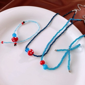 Close-up of blue beaded mushroom necklace and bracelet set on a white ceramic plate
