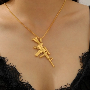 Detailed view of a gold-plated AK rifle pendant necklace worn by a fashion model