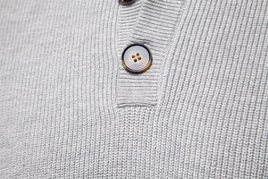 Close-up of grey knit sweater collar featuring premium texture and brown wood-style buttons