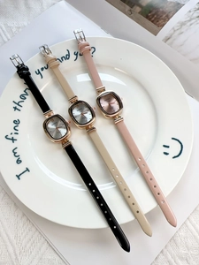 Flat lay of oval quartz watches with black, beige, and pink leather straps on a plate