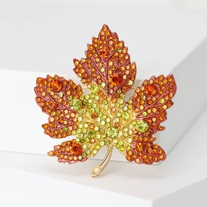 Detailed macro view of crystal maple leaf brooch with orange and yellow rhinestones
