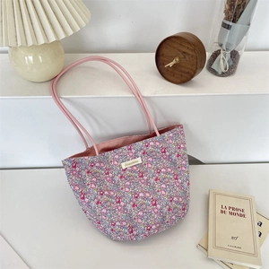 Vue détaillée du sac cabas à fleurs avec anses roses et étiquette sur un bureau