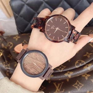 Close-up of tortoise shell and wood texture watches paired with luxury bags