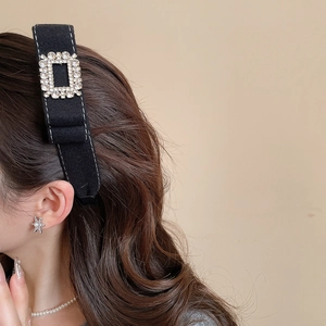 Close-up of black velvet headband with luxury square crystal buckle and pearl accessories