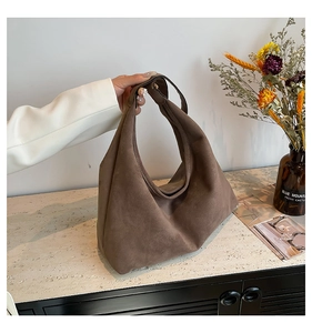 Detail of a brown suede tote bag with a minimalist design and soft matte finish