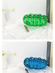 Macro detail of metallic cloud clutch bags in glossy green and blue on silk fabric