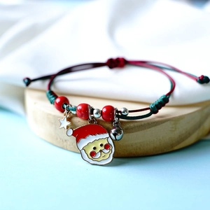 Detailed macro shot of braided Christmas bracelet with Santa charm and mini bell on wood