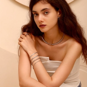 Primo piano della collana in acciaio argento minimalista e bracciali a strati sul modello