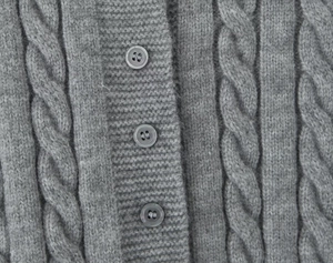Close-up of grey cable knit texture and round resin buttons on a women cardigan