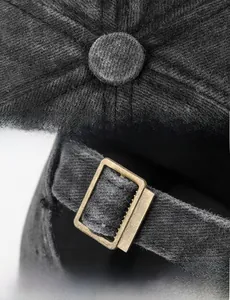 Detailed close-up of dark grey washed cotton baseball cap with adjustable metal buckle strap