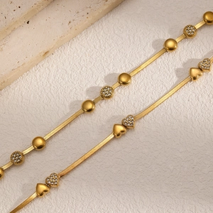 Bracelet chaîne serpent en plaqué or avec zircons et cœur sur fond de pierre