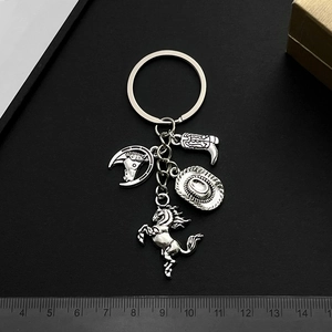 Antique silver Western cowboy keychain with hat, boot, and horse charms on black background