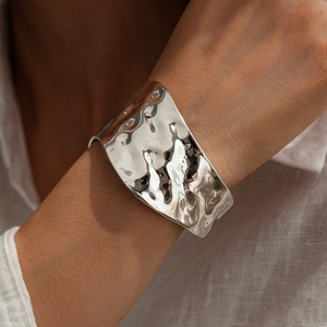 Detail of silver irregular hammered wide cuff bracelet on wrist with elegant folds