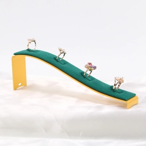 Golden butterfly and pearl rings on green velvet jewelry display stand with silk background