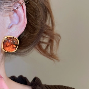 Detail of vintage square stud earring featuring amber resin and golden metal frame