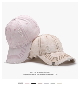 Close-up of washed cotton baseball caps in pink and beige with distressed hole details