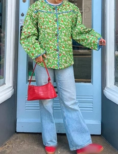 Detailed view of green floral quilted cotton jacket featuring rounded neckline and buttons