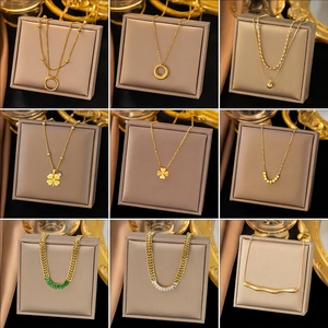 Collection of nine minimalist gold-plated titanium steel necklaces for women on display boxes