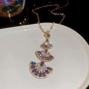 Macro detail of gold fan-shaped necklace pendants with purple pear-cut crystals