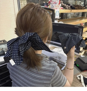 Close-up of a sweet navy blue fabric hair scrunchie with white polka dots and a bow