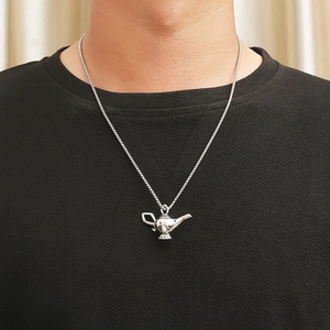 Close-up of a silver Aladdin magic lamp pendant necklace worn on a black shirt