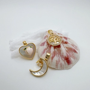 Macro detail of 18k gold heart and crescent shell pendants for jewelry making