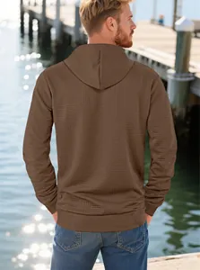 Detail of solid coffee brown men's hoodie with embossed geometric texture and ribbed cuffs