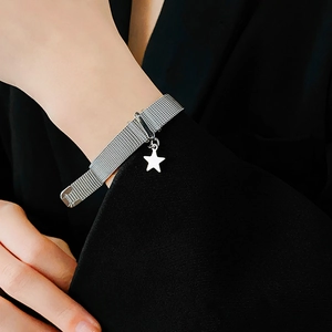 Close-up of a silver mesh star bracelet worn by a model against a black blazer background