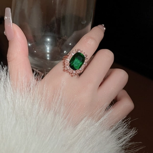 Close-up of emerald cut green gemstone ring with pavé diamonds in rose gold finish