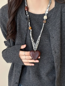 Close-up of heart wood pendant necklace with black and white print fabric strap