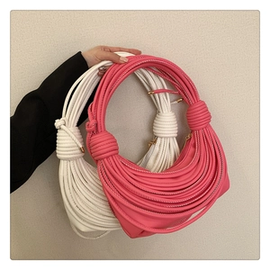 Detailed close-up of stylish knotted crescent armpit bags in pink and white PU leather