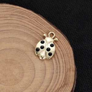 Dettaglio macro di un ciondolo a coccinella placcato oro 18K con punti in smalto nero