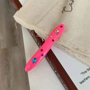 Macro shot of pink acrylic hair clip with colorful rhinestones on a vintage book