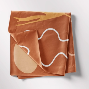 Detail of bohemian tapestry featuring caramel brown fabric with yellow abstract shapes
