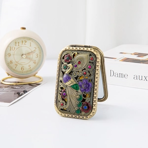 Detail of vintage bronze pocket mirror with hollow peacock pattern and colorful rhinestones