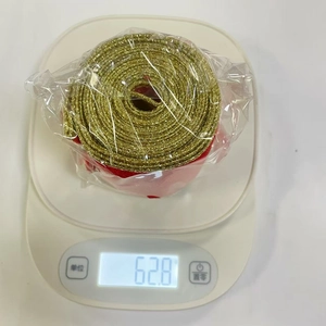 Detailed top view of gold metallic decorative ribbon roll on an electronic scale showing 62.8g