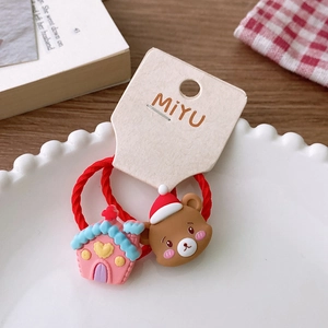 Detail of red festive hair ties with cartoon bear and house on a white plate