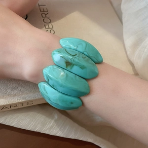 Detail of tiffany green marble pattern acrylic elastic bracelet on beige fabric background